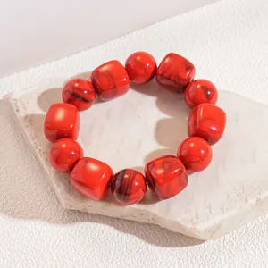 Macro view of red marbled acrylic elastic bracelet featuring round and square beads