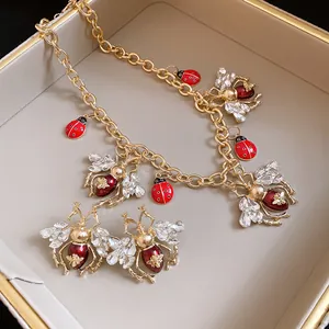 Vintage insect necklace and earrings set with rhinestones and red enamel details.