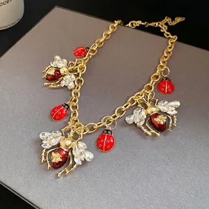 Macro view of vintage gold necklace featuring crystal-winged bees and red ladybug charms.