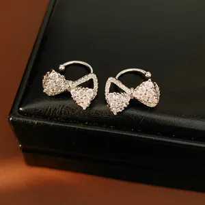 Detailed macro shot of elegant silver bow zircon clip-on earrings on a black jewelry box