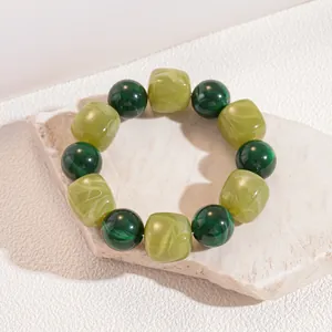 Close-up detail of vintage green marbled acrylic beaded elastic bracelet on a stone platform