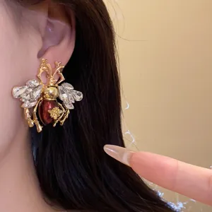 Detailed view of ornate vintage bee earring with crystals and amber resin body