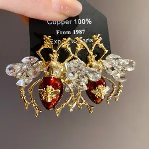 Close-up view of vintage beetle earrings featuring red enamel and sparkling crystals