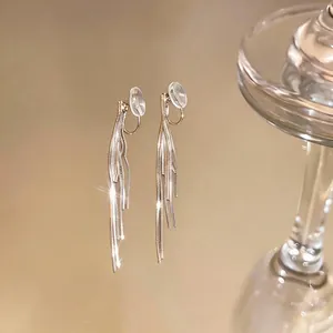 Elegant long tassel clip-on earrings with gold finish and warm reflective background display