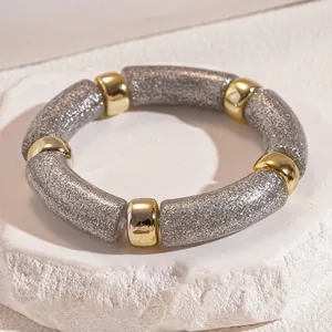 Macro view showing the silver glitter texture and gold spacers of this acrylic stretch bracelet