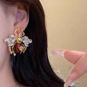 Detailed macro shot of vintage bee earring with sparkling crystals and red resin drip