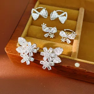 Detailed macro view of sparkling zircon butterfly and flower ear clips in a gift box
