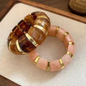 Gros plan de bracelets extensibles en résine épaisse avec des entretoises dorées