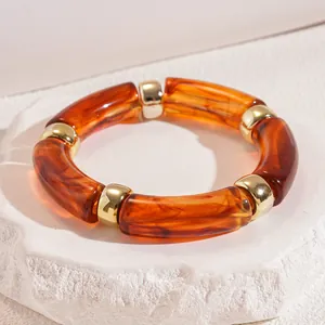 Close-up of amber acrylic elastic bracelet with gold-toned metal spacers