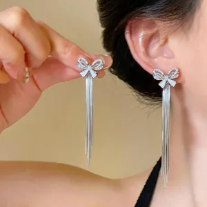 Detailed view of elegant silver bow tassel earrings with sparkling zircon accents