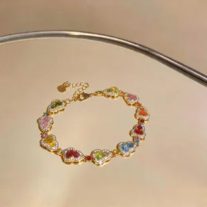 Detailansicht eines luxuriösen vergoldeten Armbands mit bunten Herz-Zirkoniasteinen