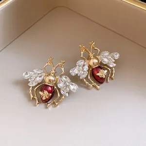 Detailed macro shot of vintage gold-toned bee earrings with red enamel and crystals