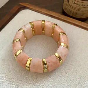 Détail montrant la texture marbre rose et les accents dorés du bracelet en résine