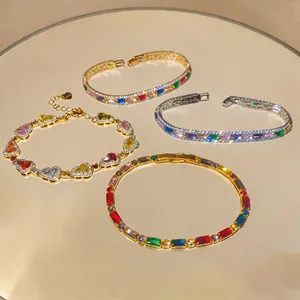 Nahaufnahme von bunten Herz- und Zirkonarmbändern auf goldenem Spiegel