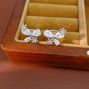 Detail of elegant silver butterfly ear clips featuring zircons and flower patterns