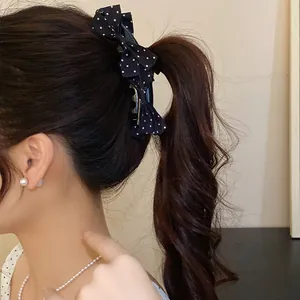 Detailed side view of a stylish polka dot bow banana hair clip on a curly ponytail