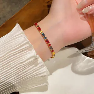 Nahaufnahme eines goldenen Armbands mit bunten rechteckigen Steinen, getragen am Handgelenk