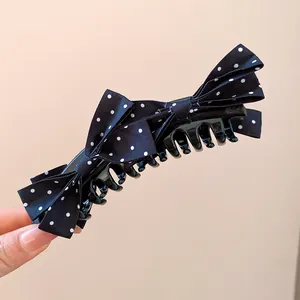 Detail view of the black polka dot bow on the elegant banana hair claw clip.