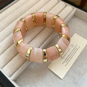 Détail d'un bracelet élastique en résine rose marbrée avec des séparateurs dorés chics