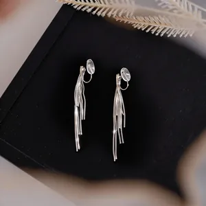 Macro view showing the detailed silver tassel chain of these elegant ear clips on a black box