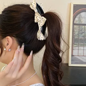 Detail view of a polka dot bow banana hair clip elegantly securing a wavy ponytail hairstyle.