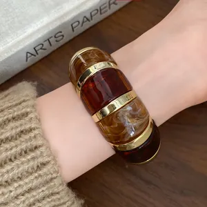 Gros plan d'un bracelet en résine avec motifs écaille de tortue et bandes métalliques dorées.