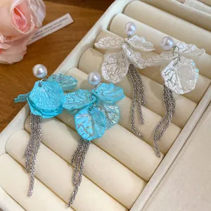 Close-up detail of pearl and petal tassel earrings with silver needles in a jewelry box