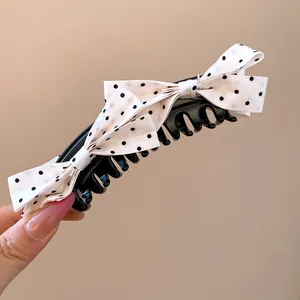 Detail of white polka dot bowknot decoration on a stylish black banana hair clip