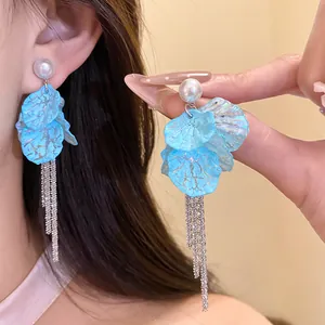 Detail showing light blue petal earrings with pearls and long silver tassels on ear