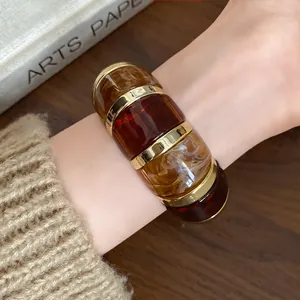 Gros plan d'un bracelet élastique en résine ambrée géométrique avec accents dorés