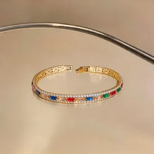 Detailaufnahme eines luxuriösen Goldarmbands mit bunten Zirkonia im Baguetteschliff und Pavé