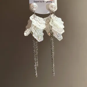 Detail of elegant pearl earrings with iridescent petals and sparkling long tassels.