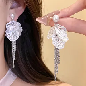 Close-up detail showing the textured white petals and long silver tassels of these earrings
