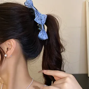 Detail view of a light blue polka dot bow banana clip styled in a wavy ponytail hairstyle