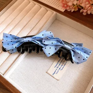 Detail view of a light blue polka dot bow banana hair clip in a jewelry box.