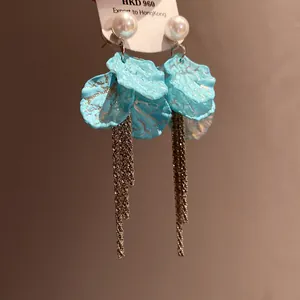 Close-up detail of elegant light blue petal tassel earrings with white pearl studs