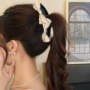 Detailed view of a sweet polka dot bow banana hair clip styled on a high ponytail