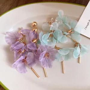 Detail of elegant mesh flower earrings with gold tassels in purple and mint green.