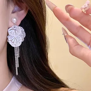 Close-up detail of elegant white petal tassel earrings with a pearl stud on a model