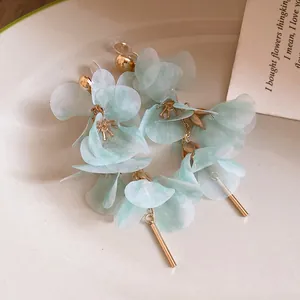 Detail shot of mint green mesh flower earrings with elegant gold bar tassels on plate