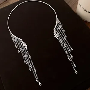 Gros plan d'un collier ras du cou argenté avec de longs glands en cristal sur noir