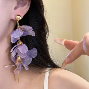 Close-up detail showing the mesh texture of purple flower tassel earrings on ear.