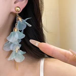 Close-up of blue mesh flower tassel earrings worn on ear with gold ball stud.
