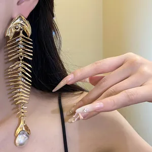 A detailed view of a large gold-toned fishbone statement earring with pearl accent