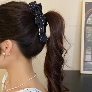 Close-up of a black polka dot bow banana clip holding a wavy ponytail hairstyle