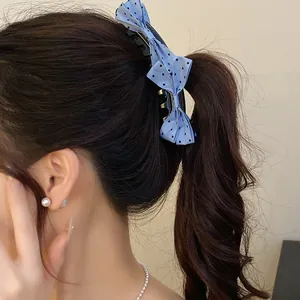 Close-up detail of a blue polka dot bow banana clip holding a ponytail securely in place.