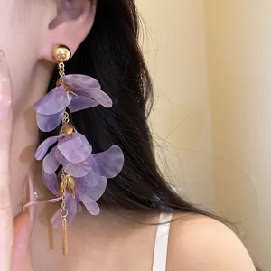 Close-up view of purple mesh flower tassel earrings with gold bar and ball details