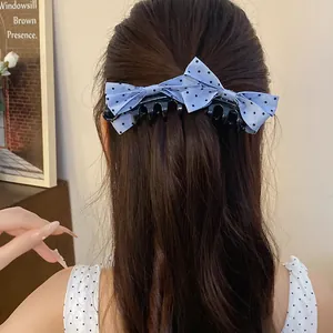 Close-up back view of a light blue polka dot bow banana clip styled in dark brown hair