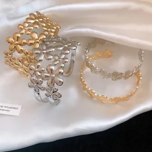 Close-up detail of retro gold and silver flower open bangles on white satin fabric