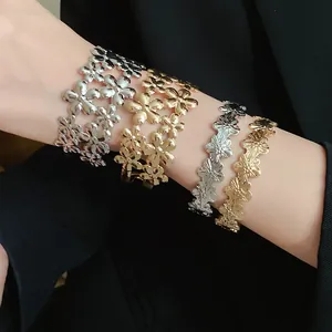Close-up of golden and silver metal floral open bangles with layered flower pattern
